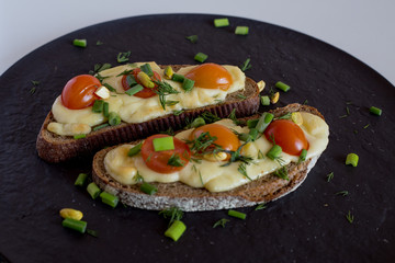 Multigrain toast bread with melt gouda or kaseri cheese and small tomatoes and green onion on top 