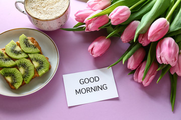 Bouquet of beautiful tulips, tasty breakfast and paper with text GOOD MORNING on color background