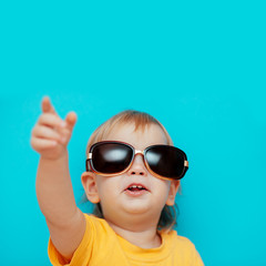 a child in black glasses looks up and points