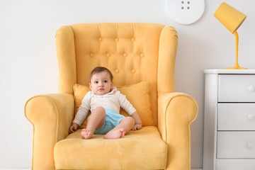 Cute little baby sitting in armchair