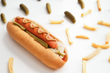 Tasty hot dog, pickled cucumbers and french fries on white background