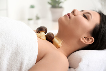 Obraz na płótnie Canvas Asian woman undergoing treatment with giant Achatina snails in beauty salon