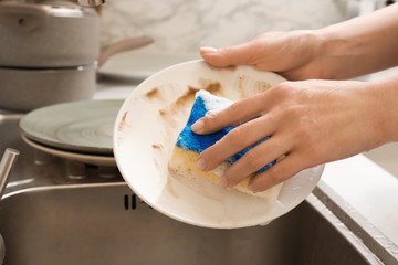 Woman washing dishes in kitchen sink