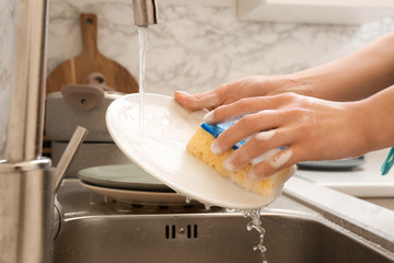 Woman washing dishes in kitchen sink