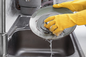 Woman washing dishes in kitchen sink