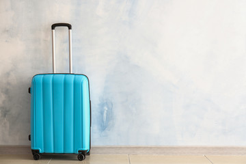 Packed suitcase near light wall