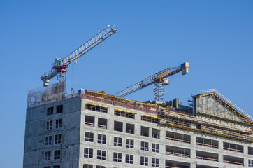 Building crane and building under construction against blue sky