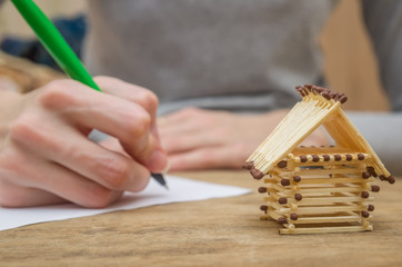 Close up wooden toy house with Woman signs a purchase contract or mortgage for a home, Real estate concept.