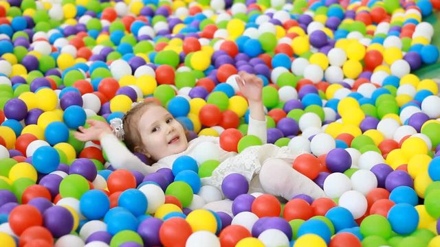 Child girl playing on the playground with multicolored balloons. Baby plays games for children.