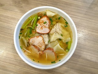 Top view of shrimp wonton with bbq pork and clear soup topped with sliced scallion in white bowl, Kiao Nam is Thai traditional