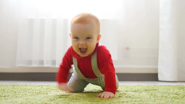 Baby Crawls Toward Rack Focus Low Angle Slow Motion. Baby crawls toward the camera in slow motion smiling and laughing in a white room