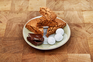 Chocolate, cranberries in sugar and almond cookies on a saucer , which stands on the board