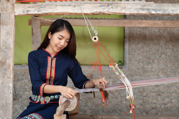 Young women weaving with traditional Thai weaving machine
