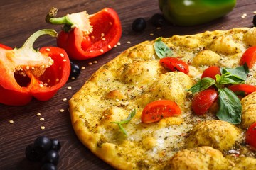 Close up top view vegetarian Italian margherita pizza melted cheese, red cherry tomatoes and fresh green basil leaves on a brown table decorated by mushrooms, black olives, pepper and arugula