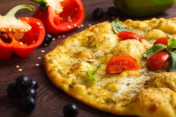 Close up top view vegetarian Italian margherita pizza melted cheese, red cherry tomatoes and fresh green basil leaves on a brown table decorated by mushrooms, black olives, pepper and arugula