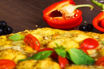 Close up top view vegetarian Italian margherita pizza melted cheese, red cherry tomatoes and fresh green basil leaves on a brown table decorated by mushrooms, black olives, pepper and arugula