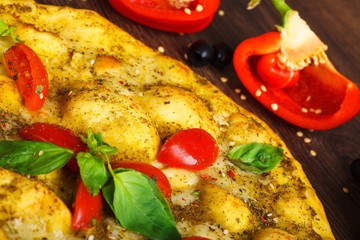 Close up top view vegetarian Italian margherita pizza melted cheese, red cherry tomatoes and fresh green basil leaves on a brown table decorated by mushrooms, black olives, pepper and arugula