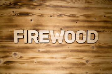 FIREWOOD word made of wooden block letters on wooden board, top view.