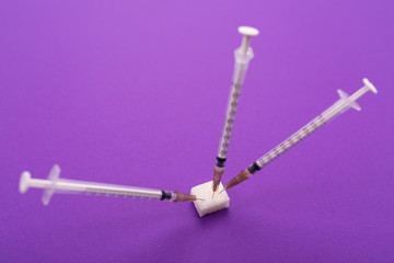 white medical syringes stick out of a piece of sugar