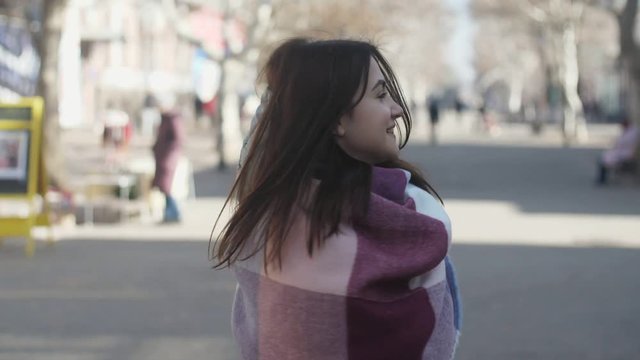 Lovely girl in striped scarf smiling and shaking her head in a street in slo-mo 