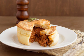 Australian meat pie on wooden table close-up with copy space, rustic style