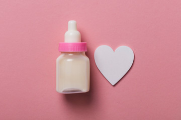 Baby bottle on a pastel pink background. New baby arrival