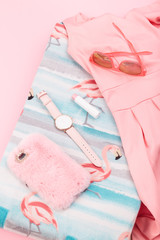 Female pink dress, mobile phone in pink case, watch with pink stripe on pink background