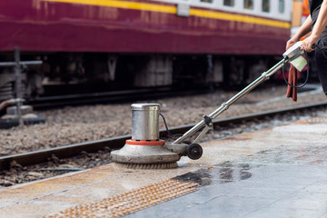 Worker using scrubber machine for cleaning and polishing floor. Cleaning maintenance train at...