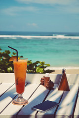 Cocktail and cellphone on the wooden table. Summer concept.