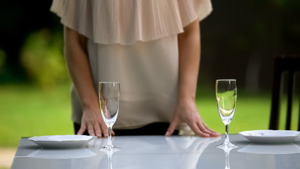 Girlfriend serving plates and wineglasses for date, family dinner outdoors