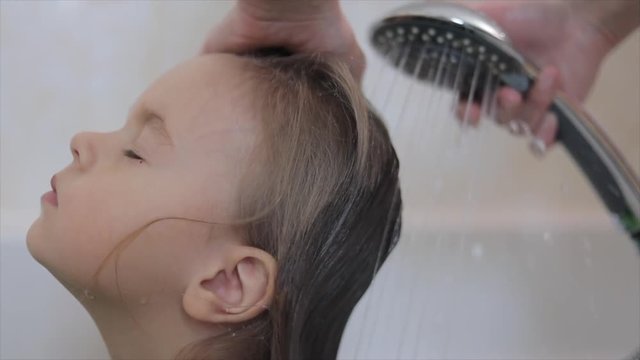 Mommy is washing baby girl in shower, close-up view