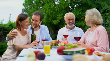 Parents and grown up children having lunch in backyard of villa, two generations