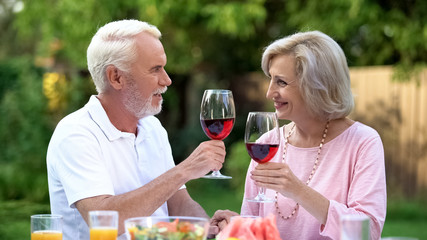 Happy old couple toasting, man complimenting beloved woman, marriage agency