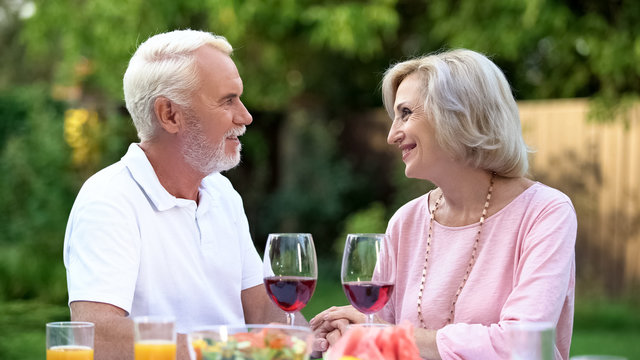 Old couple celebrating anniversary, drinking wine, everlasting love relations