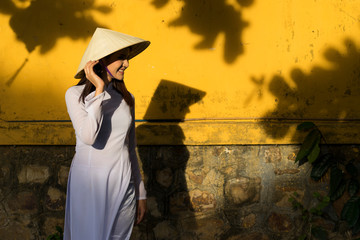 Beautiful woman with Vietnam culture traditional dress and holding hat, Ao dai is famous traditional costume, vintage style, Hoi an Vietnam.