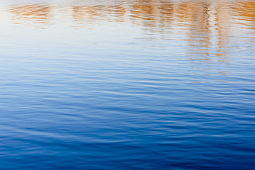 Sky, trees and buildings reflecting in the calm water of the Dnieper river in Kiev, Ukraine