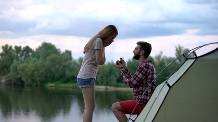 Man making proposal to beloved woman in beautiful forest during camping trip