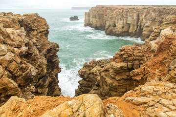 landscape of orange rocks and ocean waves Portugal, Sagres