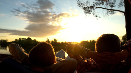 People lying and watching beautiful sunrise together, carefree days, meditation