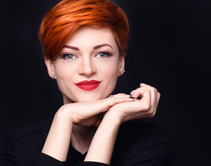 Portrait of a beautiful young red-haired woman with short hair on a dark background