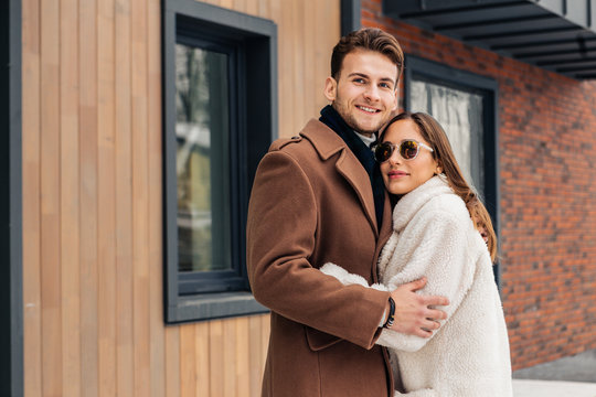 Loving girlfriend hugging her strong man while walking outside