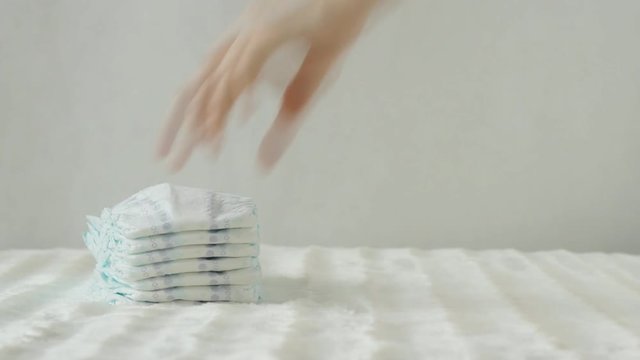 mother takes a stack of baby diapers on a white background, copy space, protection