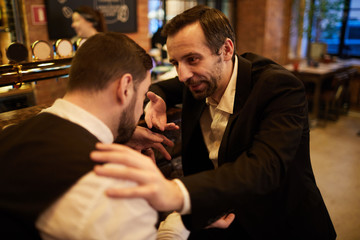 Portrait of two business people in bar chatting slightly drunk sitting by counter, copy space