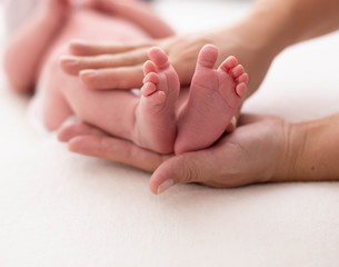 Obraz na płótnie Canvas Baby feet cupped into mothers hands. Gentle blurred background of the feet and heels of a newborn