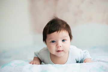 baby, newborn baby cute blue-eyed, dark hair, baby 2 months in a blue body lying on his stomach