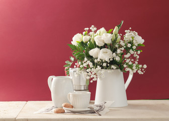 Cup of coffee and flowers composition with  ranunculus and gypsophila on beige marble table. Copyspace.