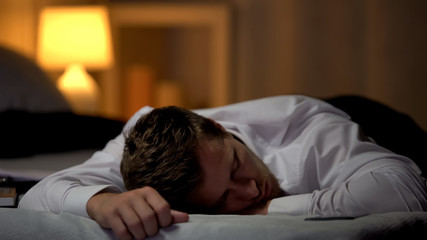 Overworked businessman fallen asleep on bed, tired after hard working day