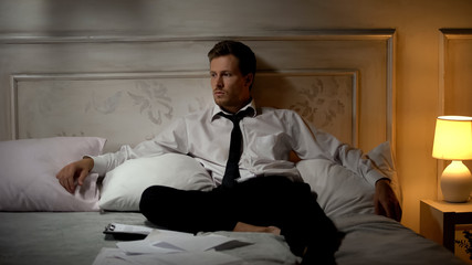 Young office worker sitting on bed, frustrated with employment termination