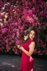 Beautiful lady stand by the big blooming tree voilet color. Happy girl with makeup in spring