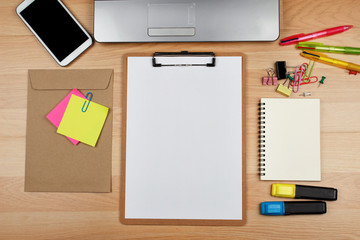 Clipboard with office supplies on wooden table, top view